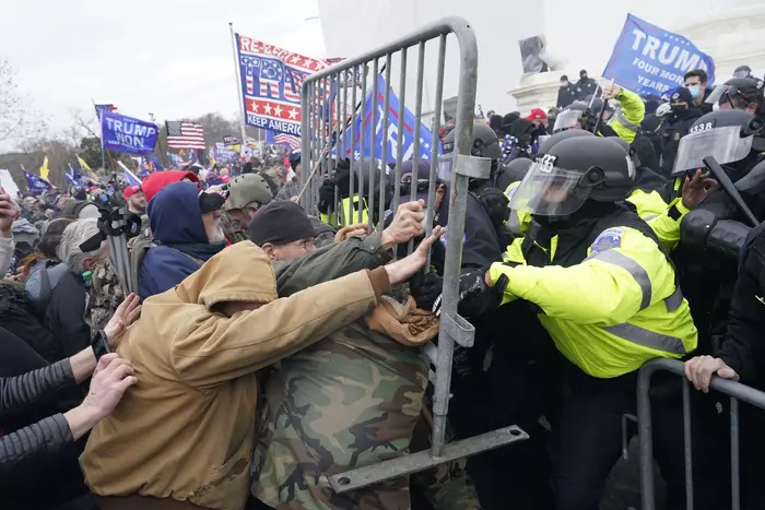 Protesters and police officers clash, with protesters pushing a barricade